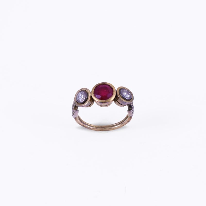Anello in oro 18K e argento con rubino centrale e due brillanti, motivi vegetali stilizzati