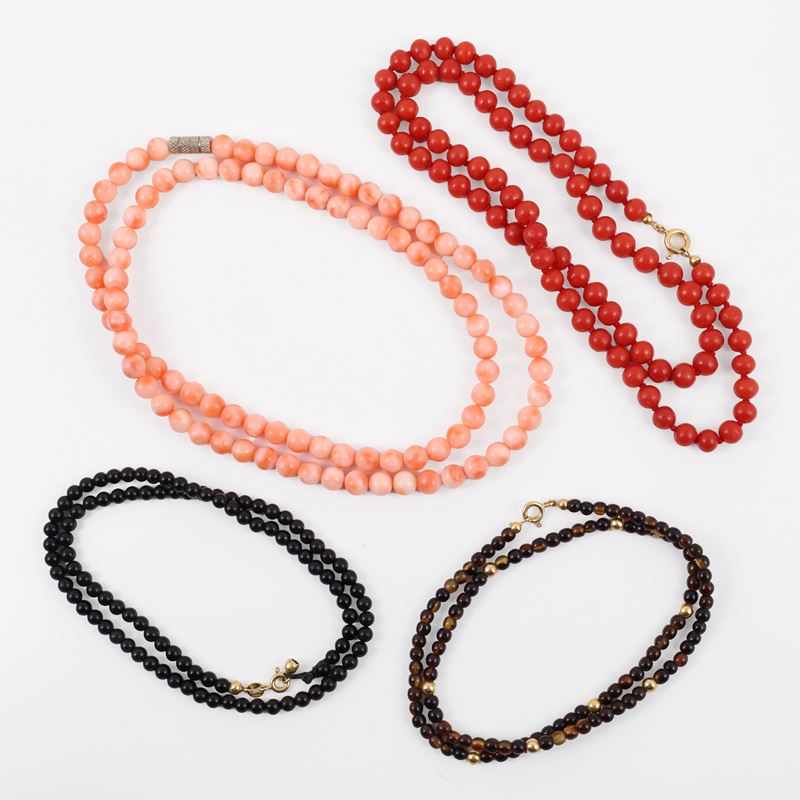 Set di quattro collane in corallo rosso, rosa, onice e ambra con chiusure in oro