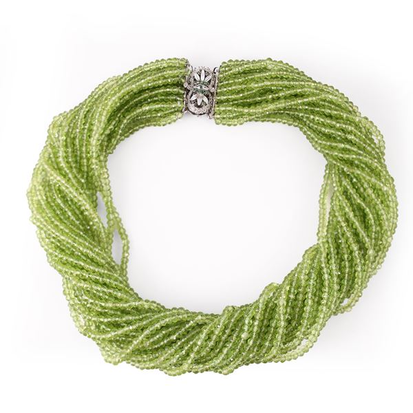 A TWENTY-FOUR-STRAND PERIDOT RONDELLE NECKLACE WITH AN 18KT GOLD CLASP SET WITH EMERALDS (one missing)